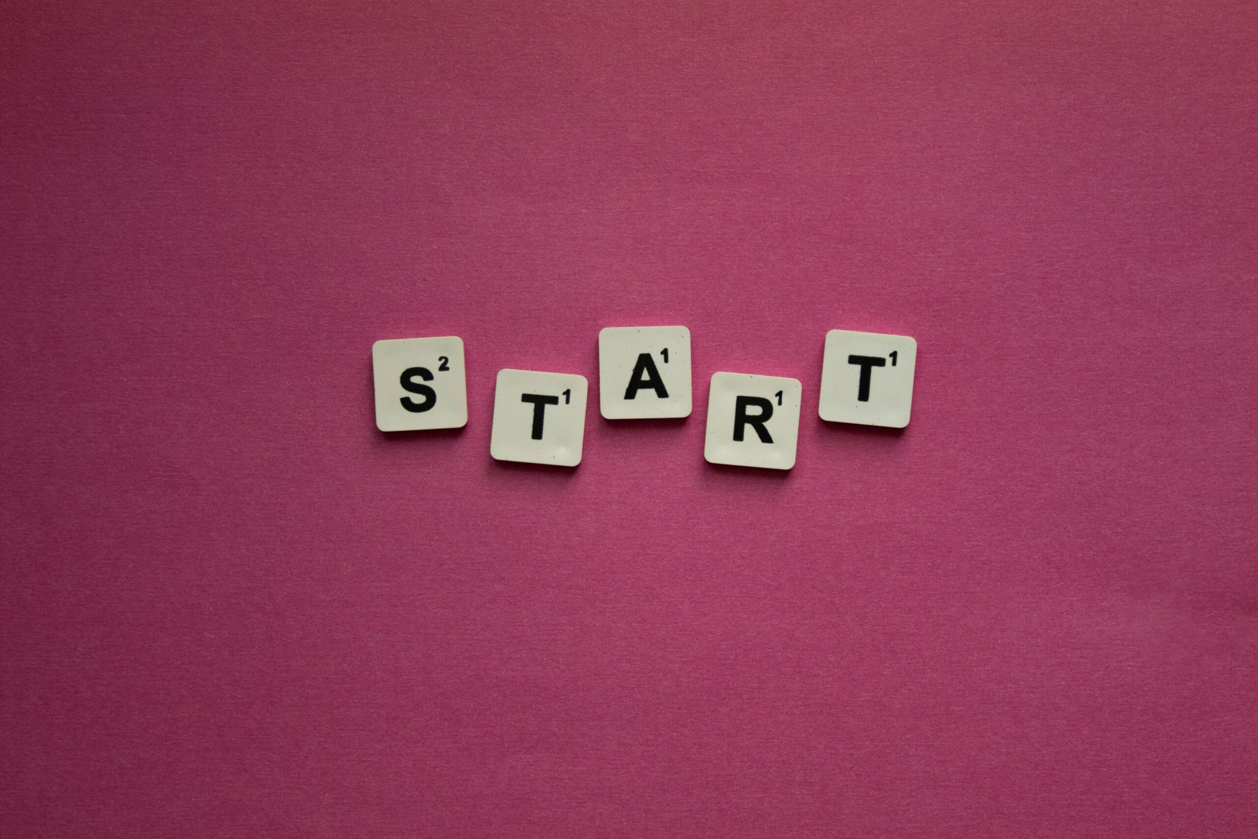 Scrabble tiles spelling 'START' against a pink background. Perfect for motivational themes.
