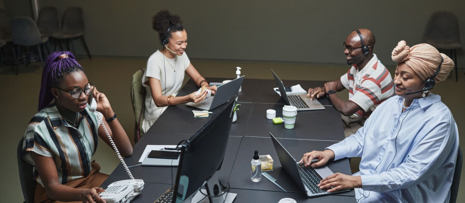 Diverse call center team working collaboratively with technology and headsets in a modern office setting.