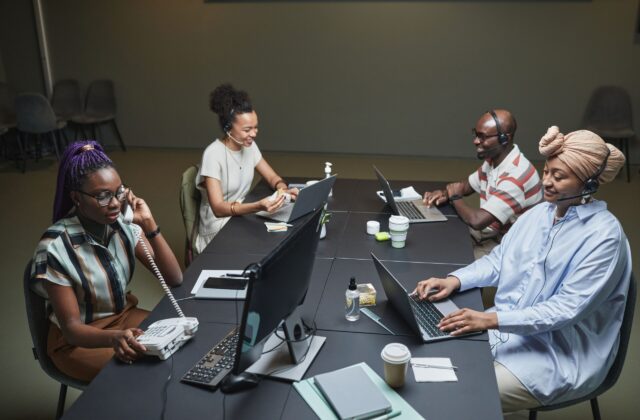 Diverse call center team working collaboratively with technology and headsets in a modern office setting.